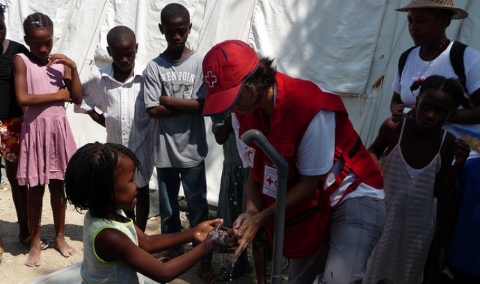 Cooperant ajudant nens. Font: British Red Cross (Flickr)