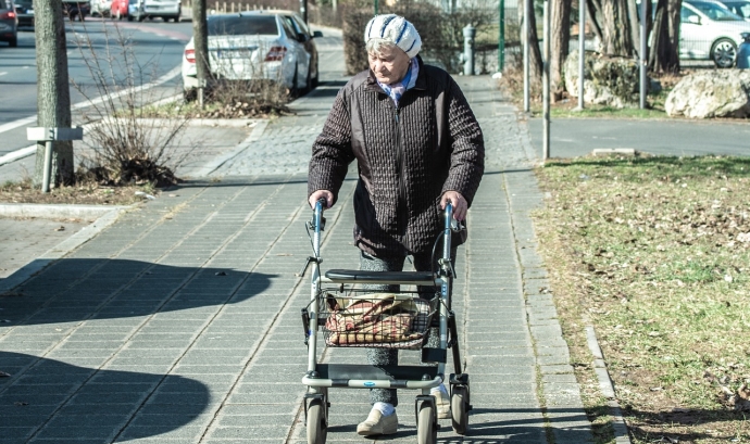 Una persona amb Alzheimer camina pel carrer amb un caminador. Font: Pixabay