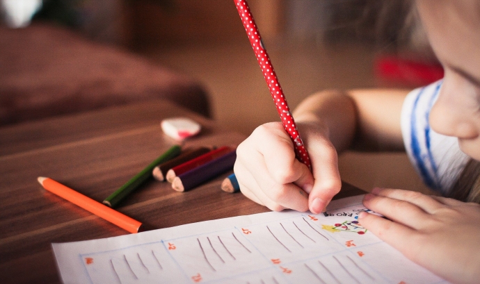 Un infant escrivint i dibuixant amb llapissos de colors. Font: Pixabay