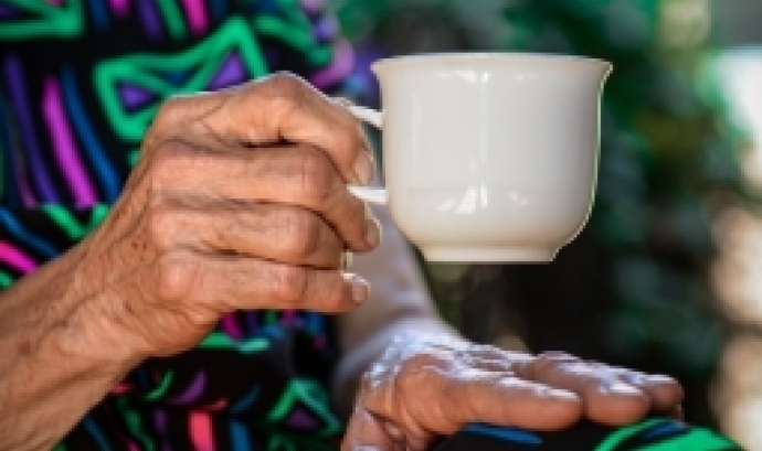 Persona gran agafant una tassa blanca amb la mà. Font: Claudia van Zil