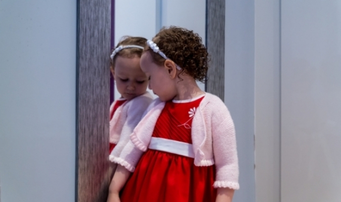 Una nena mirant-se al mirall, com a representació de la història que s'explica a l'exposició 'Cora'. Font: Adobe Stock