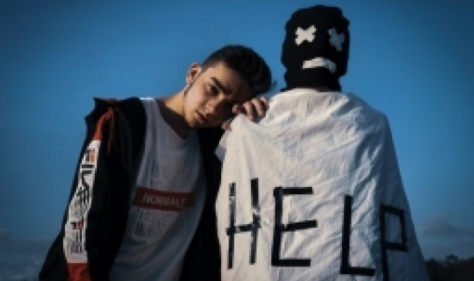 Noi arrepenjat a l'espatlla d'un altre noi amb una capa que hi diu 'Help'. Font: Iluha Zavaley