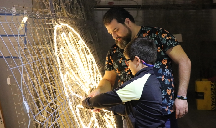 Sam Garcia, de l'Associació Carabutsí, fent un dels nous arcs de llum amb un dels participants. Font: La Traginera
