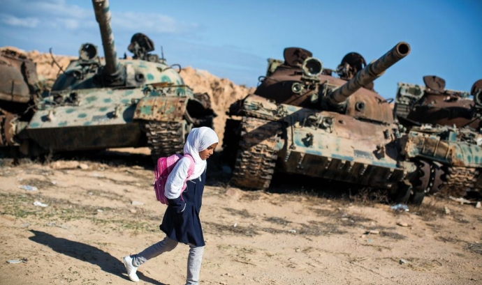 Amal al Torchani, una nena d'11 anys que en la imatge camina davant dos tancs aturats. És el camí que ha de fer per anar a l'escola, a Misrata, Líbia (Font: flickr.com - Autor: Jordi Bernabeu Farrús)