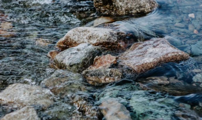Detall de les roques d'un riu, en representació del riu Ripoll. Font: Llicència CC Unsplash