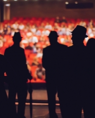 Persones en un escenari de teatre com a il·lustració de la xerrada 'L'art escènic com a eina de transformació'. Font: Adobe Stocks