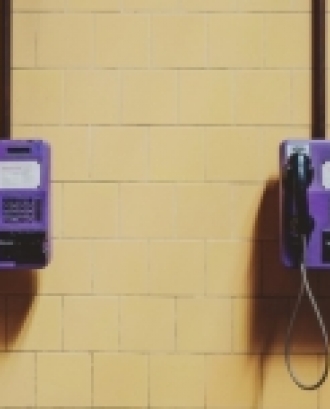 Dos telèfons de color lila penjats en una paret. Font: Brunno Tozzo