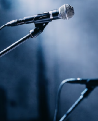 Detall d'un micròfon en un escenari com a representació del concert 'Coblism 2'. Font: Llicència CC Unsplash