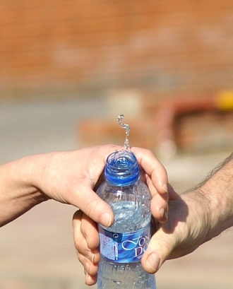 Dues mans compartint una ampolla d'aigua. Solidaritat_ferran pestaña_Flickr