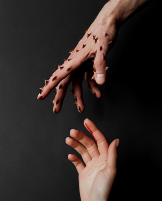 Mà plena de punxes que va a agafar un altre mà. Font: Pexels - Anna Shevchuk