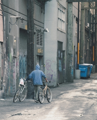 Persona portant a la mà dues bicicletes. Font: Pexels - Arnet Xavier