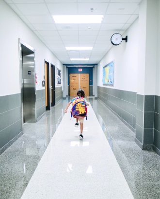 Infant corrent en un passadís d'escola. Font: Pexels - Caleb Oquendo