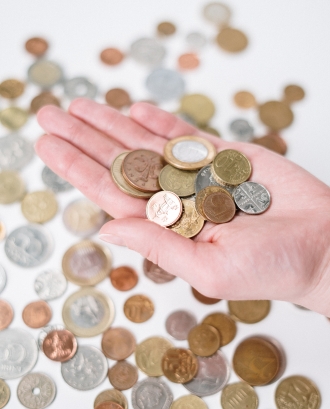 Taula amb monedes d'Euro i mà agafant-n'he. Font: Pexels - cottonbro studio