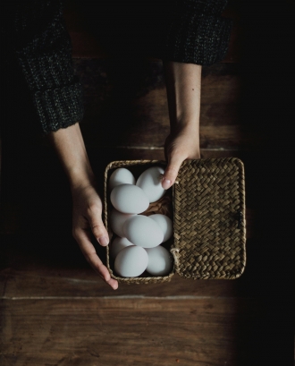Mans mostrant cistell amb ous blancs. Font: Pexels - Daniela Constantini