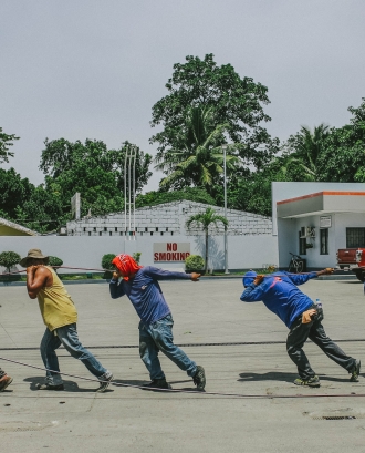 Treballadors en una benzinera, estirant una corda. Font: Pexels - Denniz Futalan