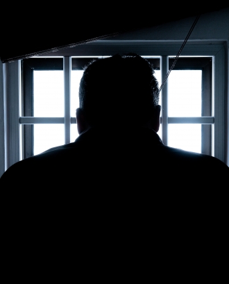 Persona mirant per una finestra amb reixa. Font: Pexels - Donald Tong
