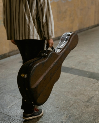 Persona transportant una guitarra en un metro. Font: Pexels - MART PRODUCTION