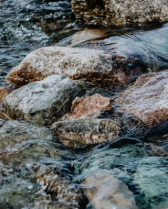Detall de les roques d'un riu, en representació del riu Ripoll. Font: Llicència CC Unsplash
